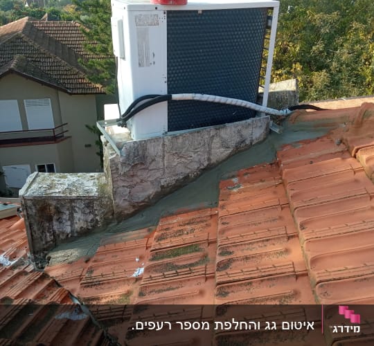 גג רעפים עם יחידת מיזוג אוויר וצינורות מחוברים